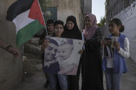 CORRECTS NAME TO MOHAMMED ABU KAFIEH - Family members of Palestinian Mohammed Abu Kafieh pose with his photos at his family house in the West Bank village of Beit Ijza, Sunday, Sept. 25, 2022 a day after he was shot and killed by Israeli forces in what Israeli army claimed was a ramming attack. Abu Kafieh's family rejected the army claim as "total lies." They said that Abu Kafieh, a 36-year-old teacher and father of three with a new business venture, would not have carried out such an attack. They said he accidentally crashed into a police car before troops opened fire. (AP Photo/Mahmoud Illean)