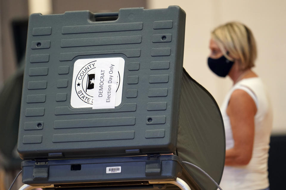 A voter walks past a voting booth before casts her ballot, Tuesday, July 14, 2020, in Houston. (AP Photo/David J. Phillip)