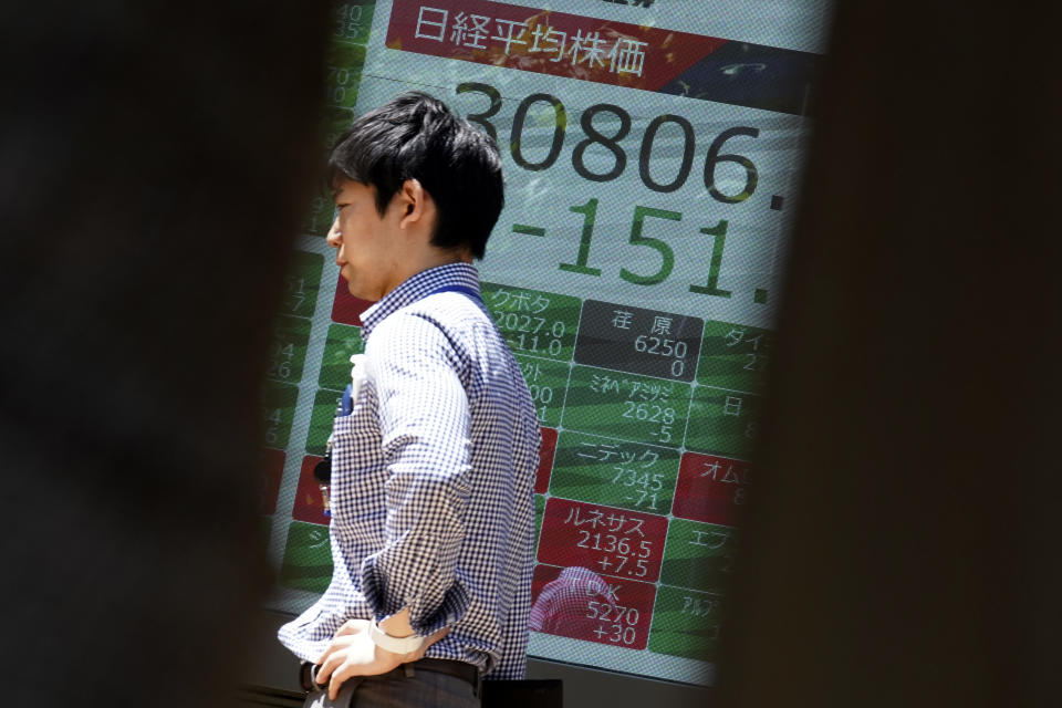 FILE - A person walks past an electronic stock board showing Japan's Nikkei 225 index at a securities firm on May 24, 2023, in Tokyo. Wages are rising in Japan more than they have in decades, at least for some workers. But so are prices, leaving many people feeling they must scrimp more than ever. (AP Photo/Eugene Hoshiko, File)