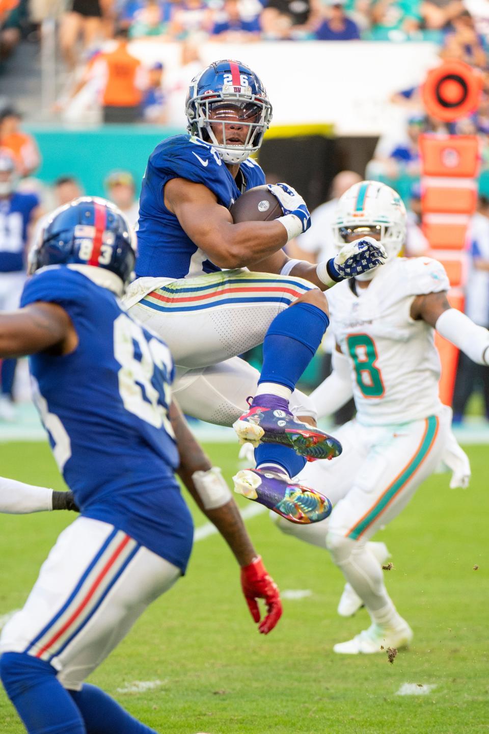 New York Giants running back Saquon Barkley (26) jumps and spins in the air as he rushes with the football during an NFL football game against the Miami Dolphins, Sunday, Dec. 5, 2021, in Miami Gardens, Fla. (AP Photo/Doug Murray)