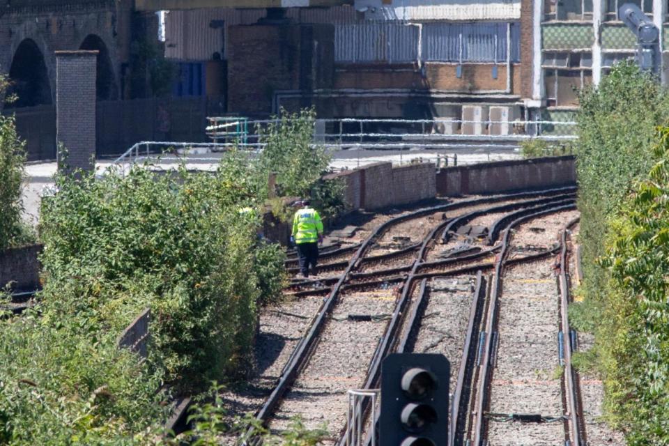 A police officer searches the tracks where three people were hit and killed by a train near Loughborough Junction