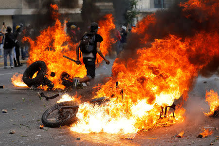 Demonstrators look on as motorcycles belonging to riot security forces are set on fire during a rally against Venezuela's President Nicolas Maduro in Caracas, Venezuela. REUTERS/Marco Bello