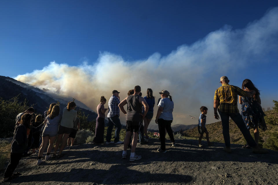 Residents watch as smoke rises from the Sheep Fire burning in Wrightwood, Calif., Sunday, June 12, 2022. (AP Photo/Ringo H.W. Chiu)