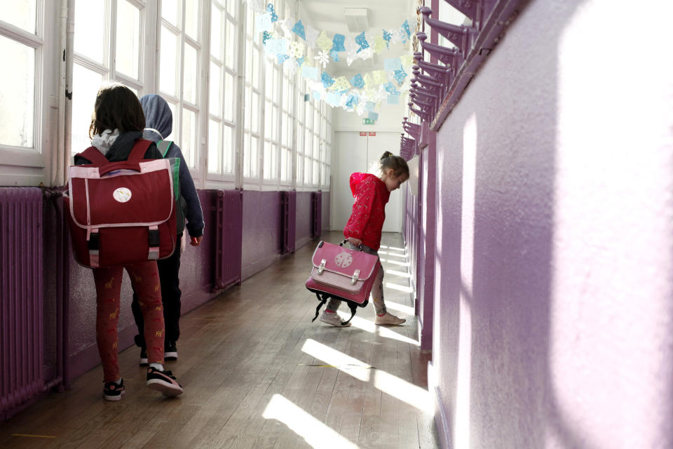 FILE - In this May 14, 2020 file photo, a child walks in her classroom as others wait outside at the Vaucanson school, in Paris. Just days after around a third of French schoolchildren went back to school, ended the gruelling coronavirus-linked lockdown, there has been flare up of about 70 cases with coronavirus in classes. (AP Photo/Thibault Camus, File)