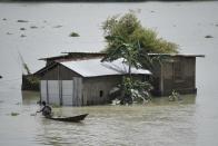 A man uses a boat to move across a flooded area in a flood effected village in Morigaon district of Assam in India on Friday, 17 July 2020. (Photo by David Talukdar/NurPhoto via Getty Images)