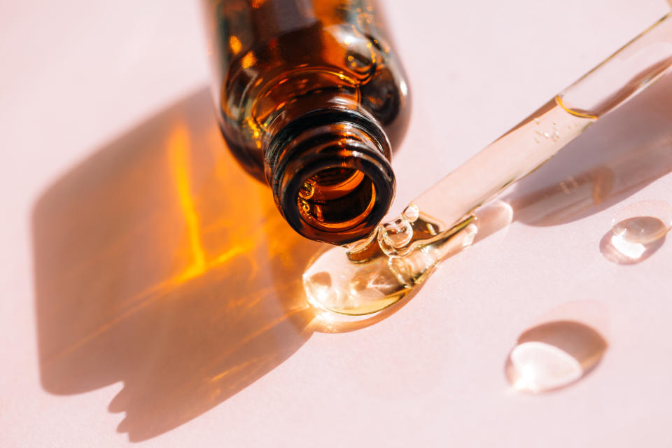 A bottle of oil being laying down next to an oil dropper