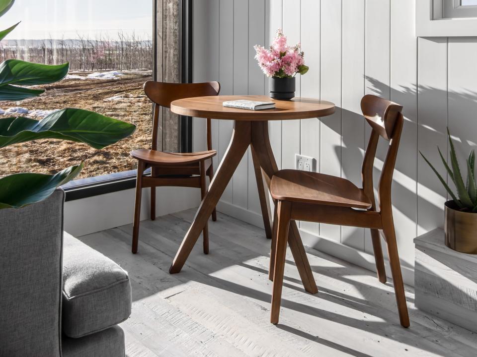 a two-person dining table across from the couch next to a large window