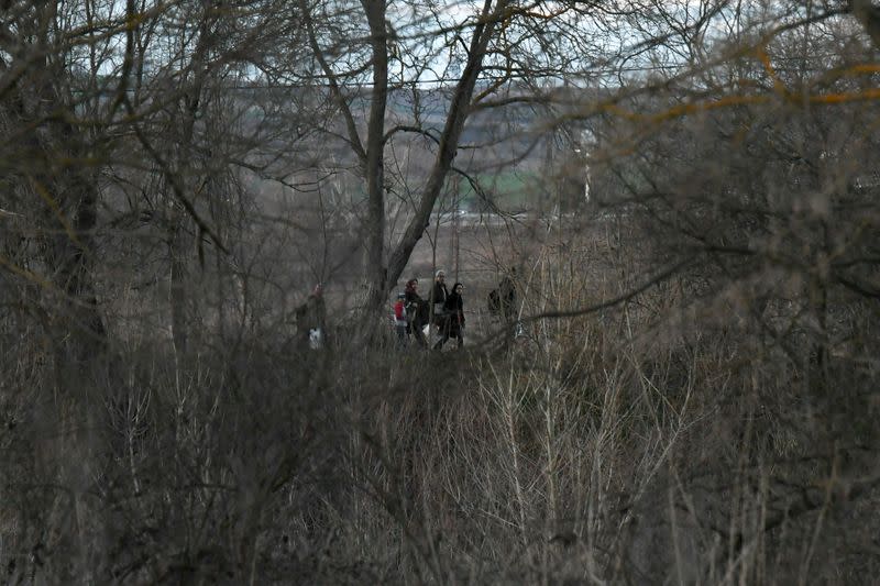 Migrants walk next to the Evros river on the Turkish side of the Greek-Turkish border, as seen from near the village of Marasia