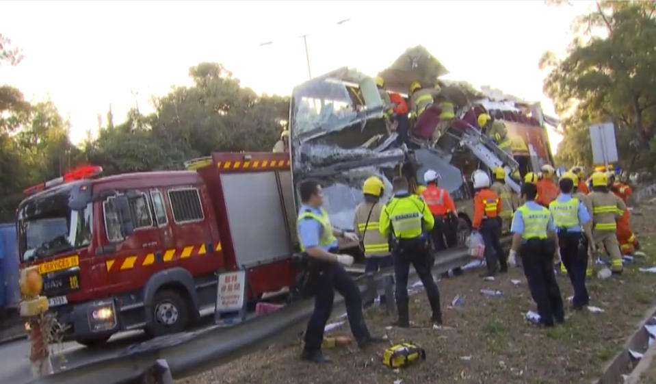 This image made from video shows a damaged bus after an accident with fire engine and emergency services around bus in Hong Kong, Wednesday, Dec. 18, 2019. The crash of a double-decker bus in Hong Kong killed multiple people, emergency services said. (TVB via AP)