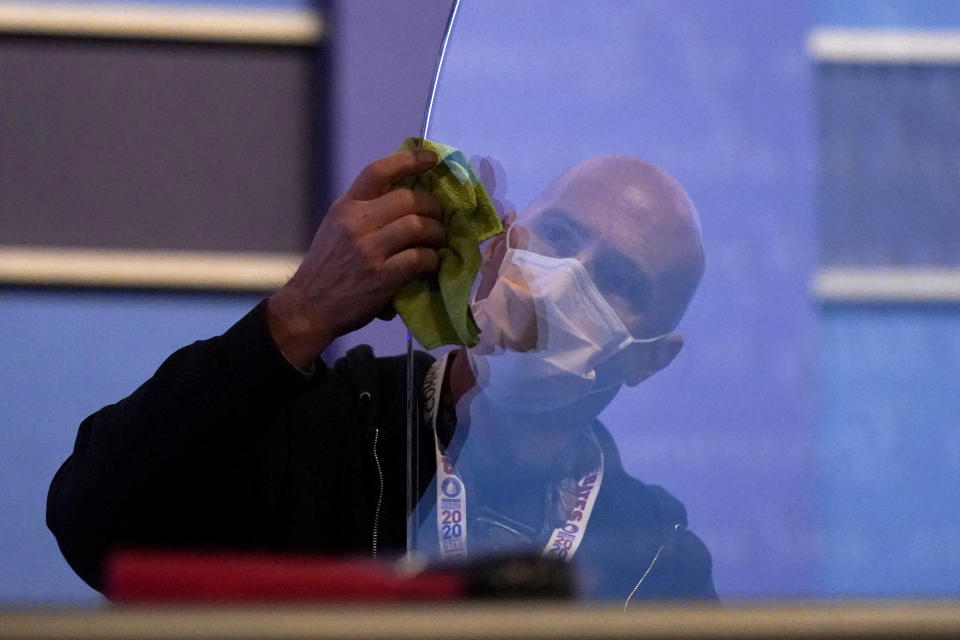 A member of the production crew cleans glass on stage which will serve as a barrier to protect the spread of COVID-19 as preparations take place for the vice presidential debate at the University of Utah, Tuesday, Oct. 6, 2020, in Salt Lake City. The vice presidential debate between Vice President Mike Pence and Democratic vice presidential candidate, Sen. Kamala Harris, D-Calif., is scheduled for Oct. 7. (AP Photo/Julio Cortez)