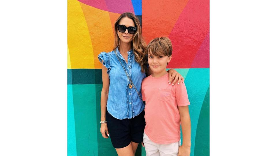 mother posing with son against mural 