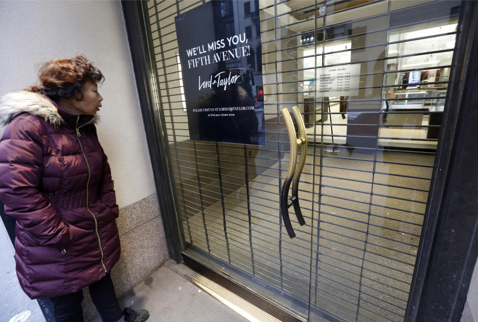 FILE - In this Jan. 2, 2019, file photo a woman pauses to read a farewell sign from outside Lord & Taylor's flagship Fifth Avenue store which closed for good in New York. Over the last year or so, Gap, Tommy Hilfiger, Lord & Taylor and Polo Ralph Lauren have closed their flagship stores on Manhattan’s Fifth Avenue. (AP Photo/Kathy Willens, File)