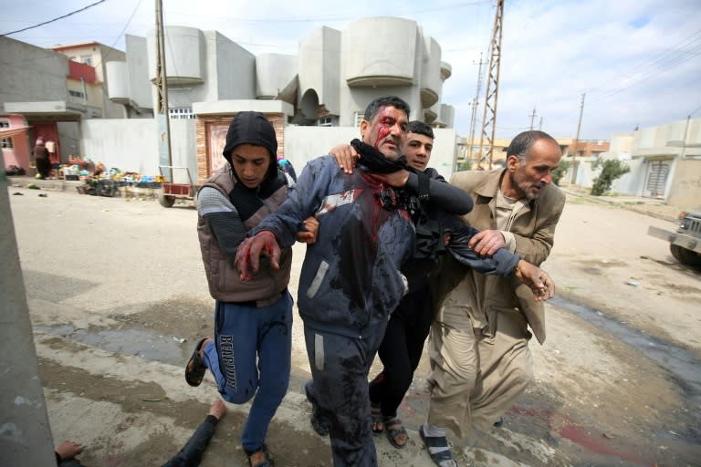 Iraqi civilians help a man who was injured by a mortar shell fired by Islamic State group jihadists on civilians who were gathered to receive aid, in Al-Risala neighbourhood on March 22, 2017