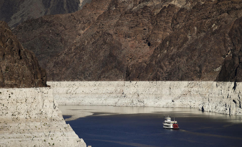 FILE - In this Oct. 14, 2015, file photo, a riverboat glides through Lake Mead on the Colorado River at Hoover Dam near Boulder City, Nev. For the seven states that rely on the Colorado River that carries snowmelt from the Rocky Mountains to the Gulf of California, that means a future with increasingly less water for farms and cities although climate scientists say it's hard to predict how much less. The U.S. Bureau of Reclamation on Thursday, Aug. 15, 2019, will release its projections for next year's supply from Lake Mead, which feeds Nevada, Arizona and California. (AP Photo/Jae C. Hong, File)