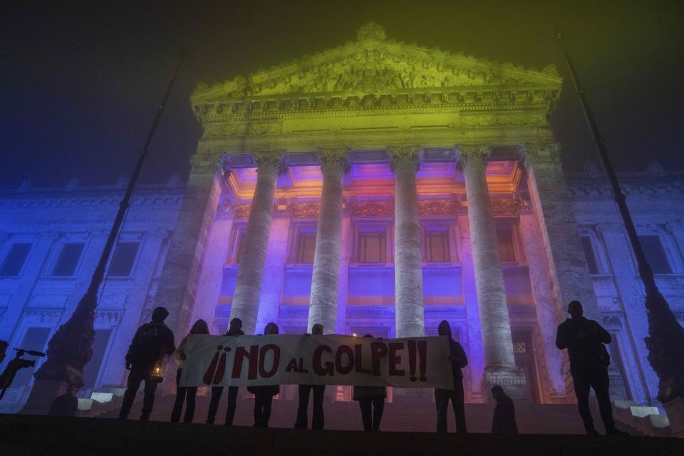 Varias personas sostienen un cartel de rechazo en el 50o aniversario del golpe de Estado de 1973, al frente del Palacio Legislativo en Montevideo, Uruguay, el martes 27 de junio de 2023. (AP Foto/Matilde Campodónico)