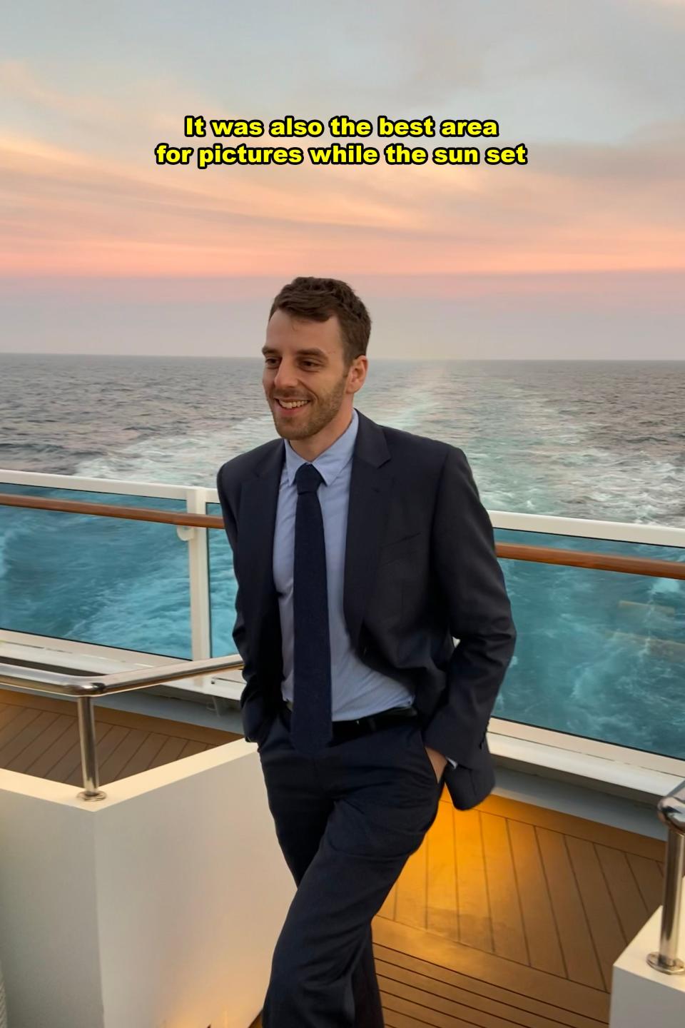 Man in suit smiles on a ship deck during sunset; text says 