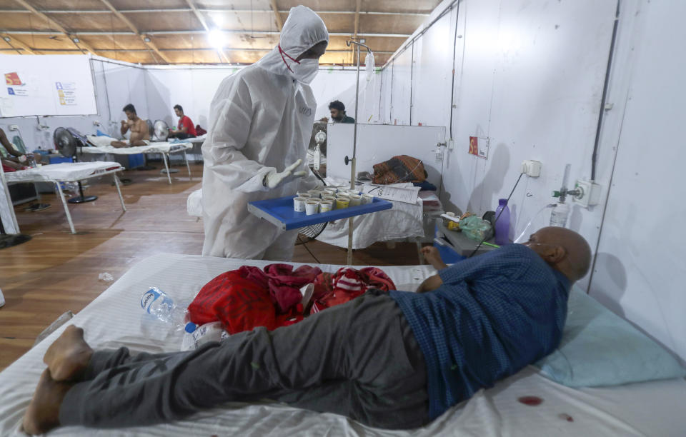 A health worker offers tea to a patient at the BKC jumbo field hospital, one of the largest COVID-19 facilities in Mumbai, India, Friday, May 7, 2021. (AP Photo/Rafiq Maqbool)