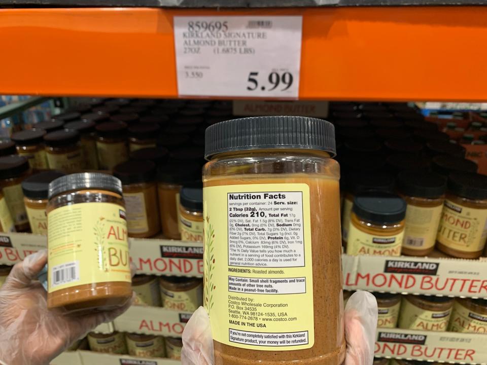 hands holding jars of almond butter at costco
