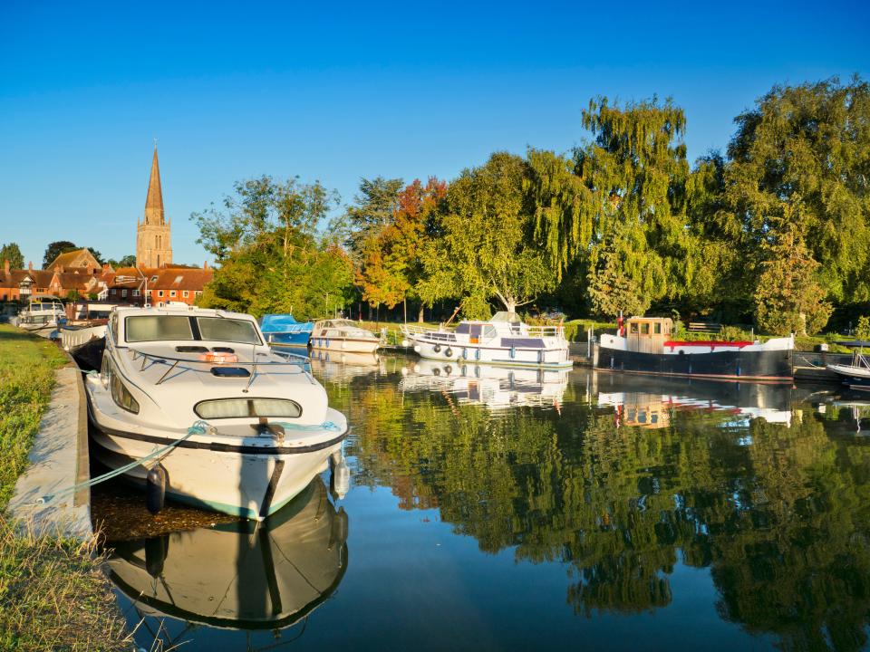 Houseboats floating on the Thames river at Abingdon, looking towards St Helen's Church.
