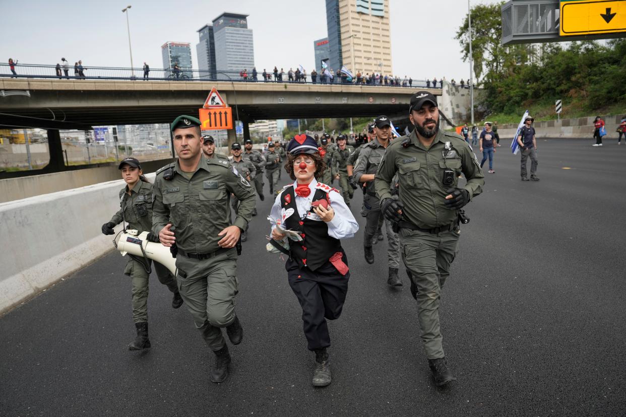 An Israeli activist dressed as a clown runs with border police (Copyright 2023 The Associated Press. All rights reserved.)