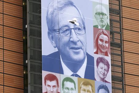 A bird flies past a banner, showing an image of the European Commission's new President Jean-Claude Juncker, on the facade of the European Commission headquarters in Brussels in this November 4, 2014 file photo. REUTERS/Francois Lenoir/Files