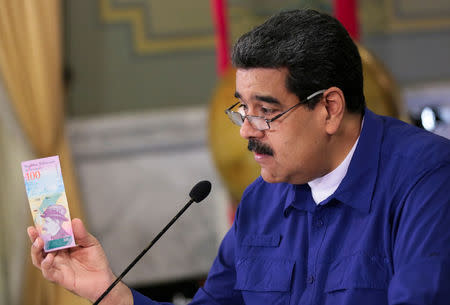 Venezuela's President Nicolas Maduro holds a bank note of the new Venezuela's currency Bolivar Soberano (Sovereign Bolivar) as he speaks during a meeting with ministers at Miraflores Palace in Caracas, Venezuela July 25, 2018. Miraflores Palace/Handout via REUTERS