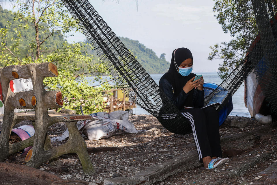 Nur Alea Soffiyyah Ahmad Hanif attends online classes in front of her house on Pulau Aman January 22, 2021. — Picture by Sayuti Zainudin