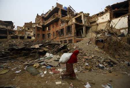 A woman, carrying goods, walks past collapsed houses following April 25 earthquake at Bhaktapur May 7, 2015. REUTERS/Navesh Chitrakar