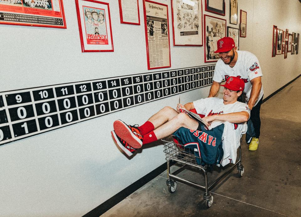 Yolmer Sanchez gives Ryan Fitzgerald a ride along the wall mural depicting the scoreboard commemorating the longest game between the PawSox and Rochester Red Wings in 1981.