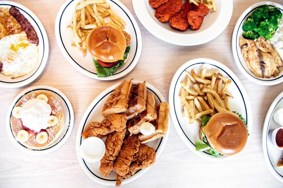 An overhead photo of dishes from the halal menu, including pancakes with turkey bacon, grilled chicken sandwich and a burger.