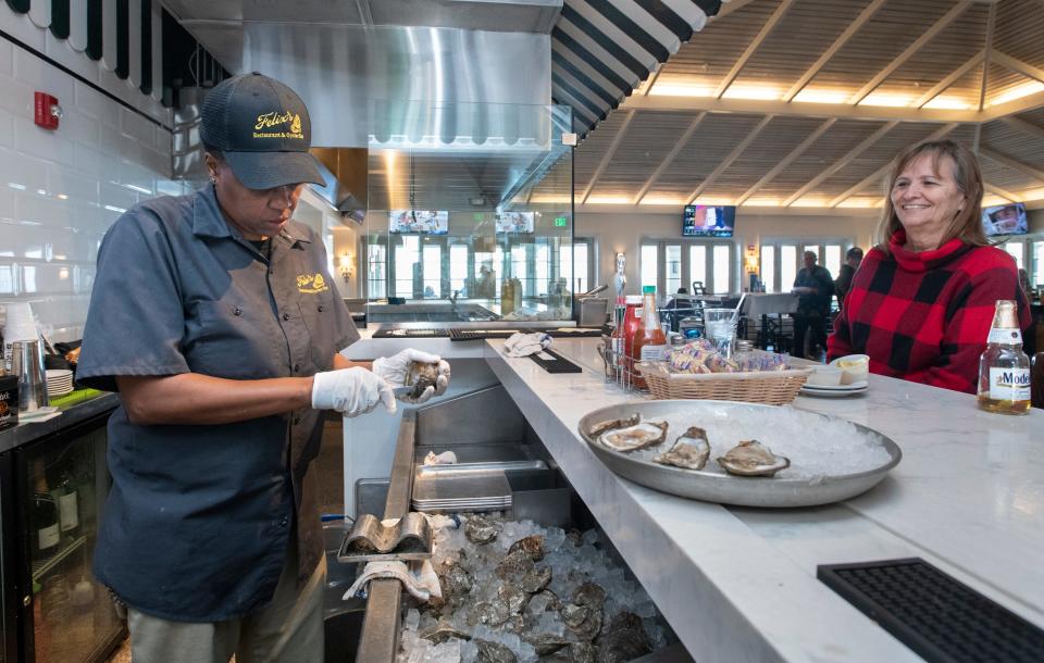 Maryjane Marion, of Lillian, Alabama, right, looks on as Yvette Lawrence shucks oysters Monday at Felix's Restaurant & Oyster Bar at the Pensacola Beach Boardwalk.