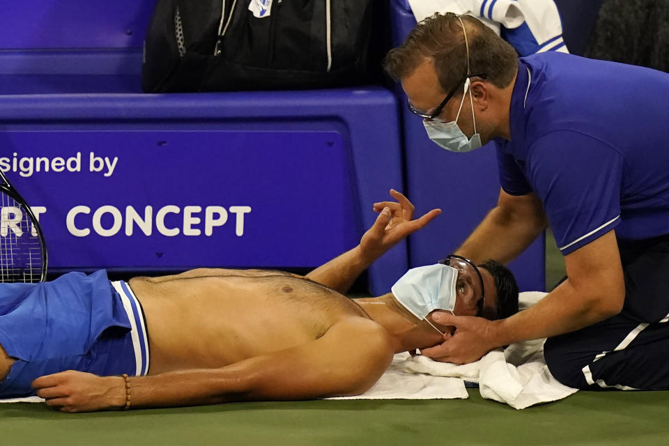 Un fisioterapeuta da tratamiento en el cuello a Novak Djokovic durante un partido del Abierto Western & Southern, el martes 25 de agosto de 2020, en Nueva York. (AP Foto/Frank Franklin II)