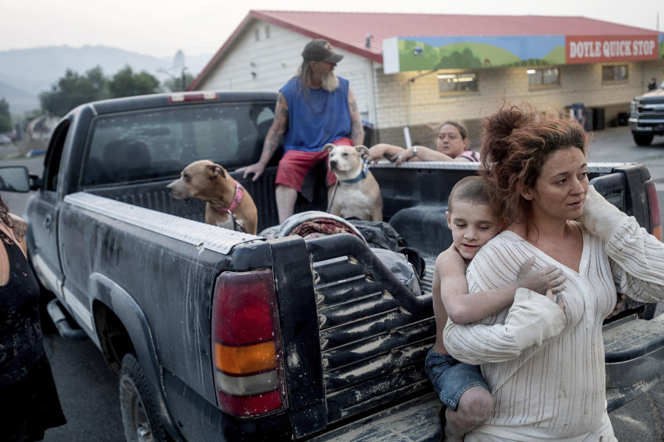 Destiney Barnard holds Raymond William Goetchius while stranded at a gas station near the Dixie Fire on Tuesday, Aug. 17, 2021, in Doyle, Calif. Barnard was helping Goetchius and his family evacuate from Susanville when her car broke down. (AP Photo/Noah Berger)