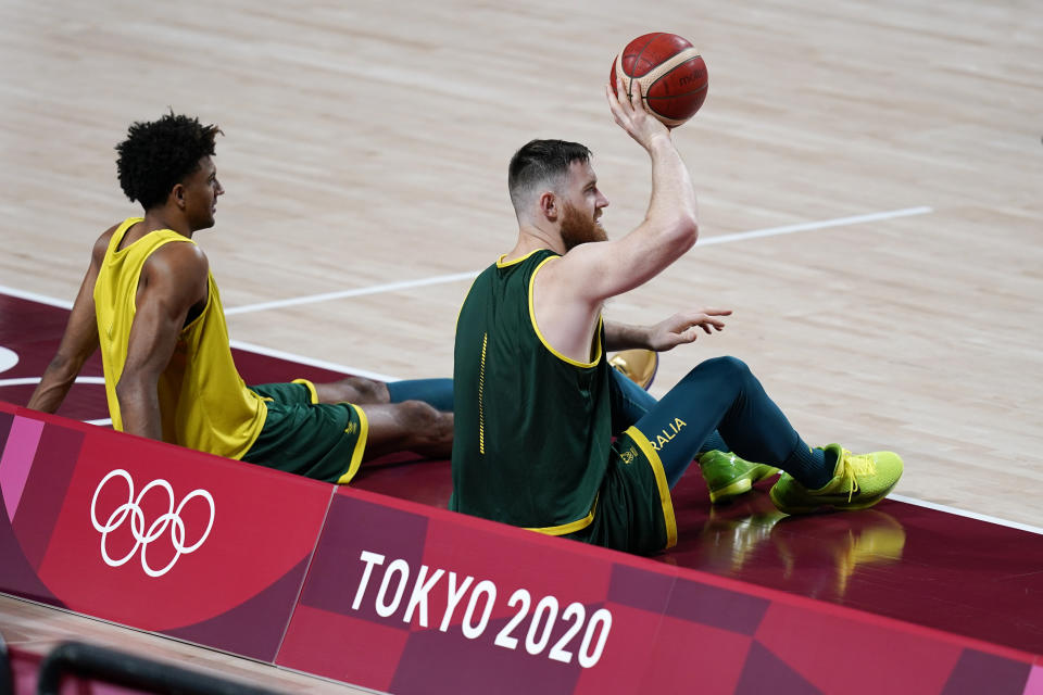 Australia's Aron Baynes, right, and Matisse Thybulle sit on the court during a men's basketball practice at the 2020 Summer Olympics, Friday, July 23, 2021, in Saitama, Japan. (AP Photo/Charlie Neibergall)