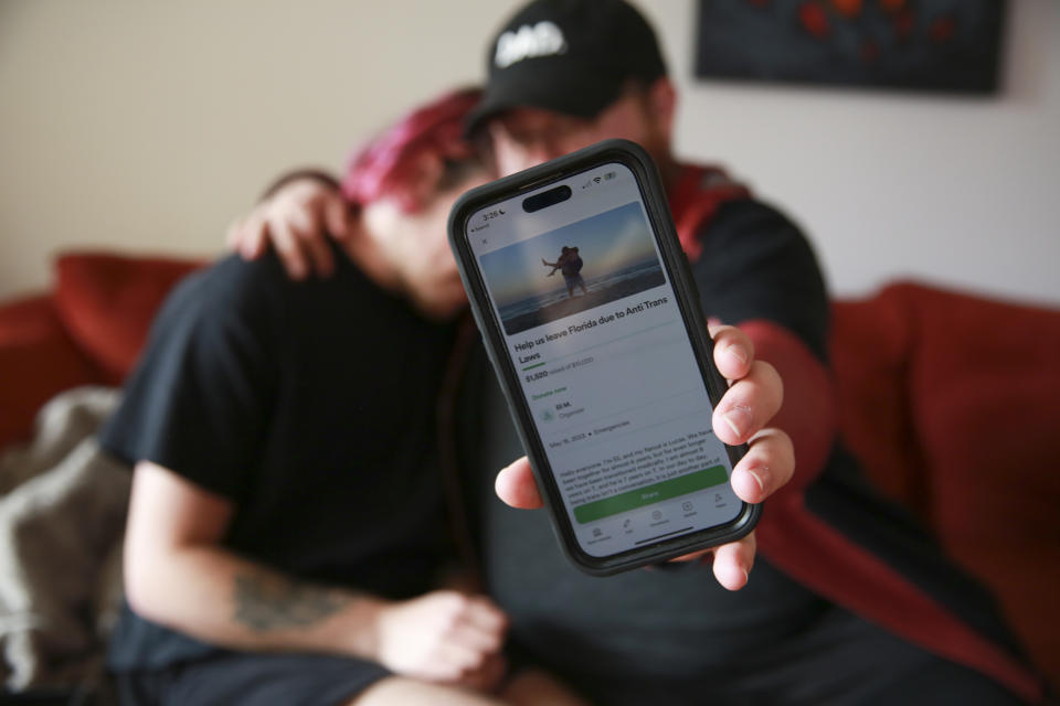 Lucas and Eli show their GoFundMe campaign to raise funds to leave the state for Minnesota as they sit at their home in Casselberry, Fla. May 29, 2023. The Associated Press is not using Eli’s and Lucas’ last names because they fear reprisal. Lucas is no longer able to access gender affirming care through his provider due to recent legislation in Florida that prevents nurse practitioners from providing care. (AP Photo/Laura Bargfeld)