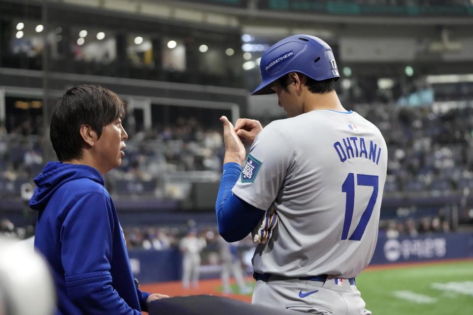 Los Angeles Dodgers designated hitter Shohei Ohtani, right, talks to his interpreter Ippei Mizuhara during the fifth inning of an opening day baseball game against the San Diego Padres at the Gocheok Sky Dome in Seoul, South Korea Wednesday, March 20, 2024, in Seoul, South Korea. (AP Photo/Lee Jin-man)