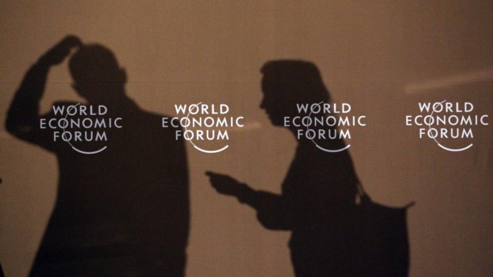 Shadows of participants of the World Economic Forum are seen on a wall in Davos