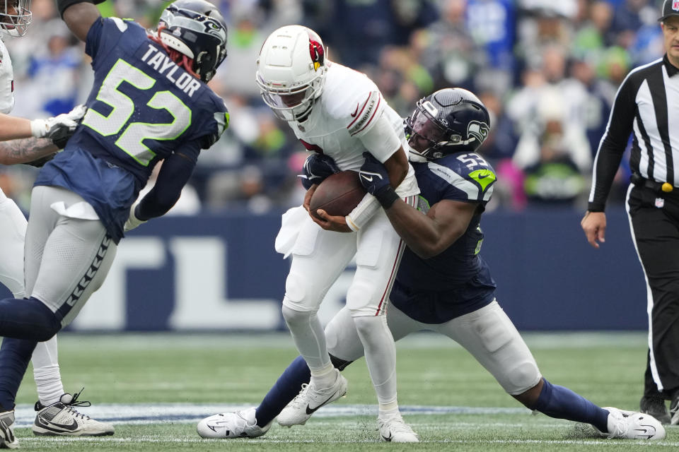 Arizona Cardinals quarterback Joshua Dobbs, center, gets taken down by Seattle Seahawks linebacker Boye Mafe (53) as Seahawks linebacker Darrell Taylor (52) arrives to join in on the tackle during the second half of an NFL football game Sunday, Oct. 22, 2023, in Seattle. (AP Photo/Lindsey Wasson)