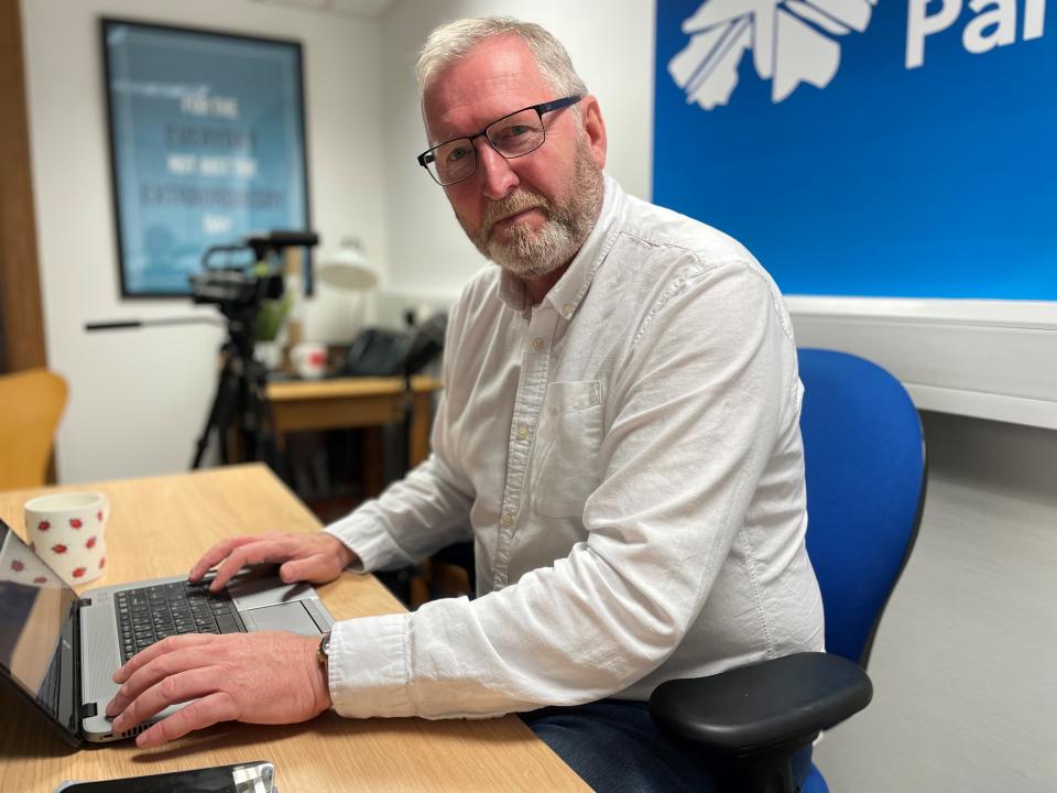 Doug Beattie sitting at a desk with a laptop in his constituency office in Portadown