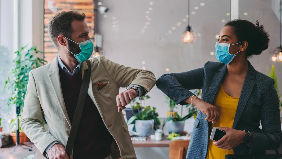 Colleagues in the office practicing alternative greeting to avoid handshakes during COVID-19 pandemic.