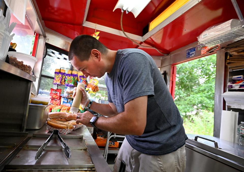 Justin Wnukowski prepares hot dogs in his 6-by-10-foot hot dog stand at 80 Worcester St. Wednesday.