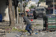 A Palestinian demonstrator holds rocks as the Israeli army carries out an operation in the West Bank town of Nablus, Tuesday, Aug. 9, 2022. (AP Photo/Majdi Mohammed)