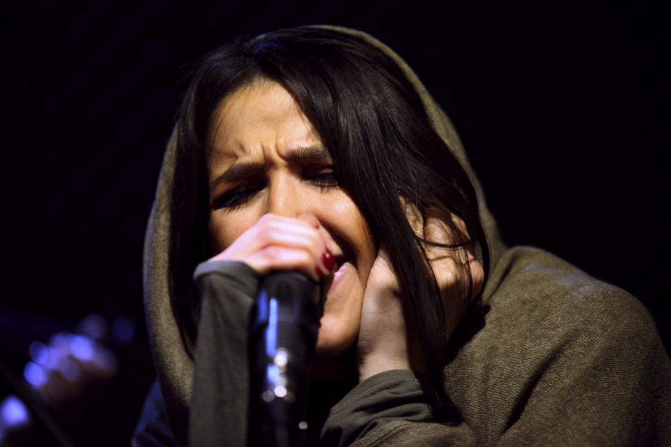 In this picture taken on Friday, Jan. 25, 2013, female Iranian back vocalist Azadeh Ettehad, a member of a band called "Accolade," sings a song in an unauthorized stage performance in Tehran, Iran. Headphone-wearing disc jockeys mixing beats. It’s an underground music scene that is flourishing in Iran, despite government restrictions. (AP Photo/Vahid Salemi)