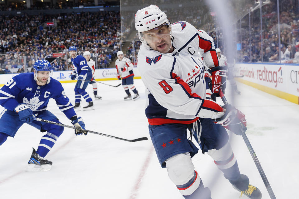 Washington Capitals left wing Alex Ovechkin (8) skates a puck out of the corner as Toronto Maple Leafs center John Tavares defends during the third period of an NHL hockey game in Toronto on Sunday, Jan. 29, 2023. (Cole Burston/The Canadian Press via AP)