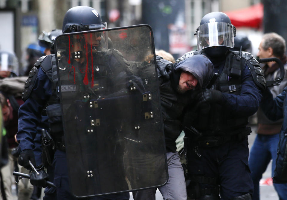 FILE - In this Oct. 10, 2017 file photo, riot police officers detain a demonstrator during a protest in Paris. As videos helped reveal many cases of police brutality, French civil rights activists voiced fears that a new security law would threaten efforts by people from minorities and poor neighborhoods to document incidents involving law enforcement officers. French President Emmanuel Macron's government is pushing a new security bill that would notably make it illegal to publish images of officers with intent to cause them harm. (AP Photo/Francois Mori, File)