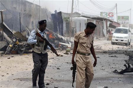 Somali policemen walk around the scene of an explosion near the entrance of the airport in Somalia's capital Mogadishu February 13, 2014. REUTERS/Feisal Omar