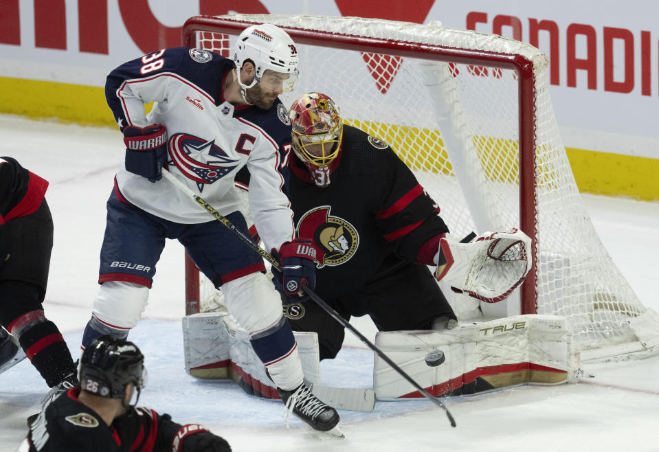 Columbus Blue Jackets center Boone Jenner tries to tip the puck past Ottawa Senators goaltender Anton Forsberg during the first period of an NHL hockey game, Tuesday, Feb. 13, 2024, in Ottawa, Ontario. (Adrian Wyld/The Canadian Press via AP)