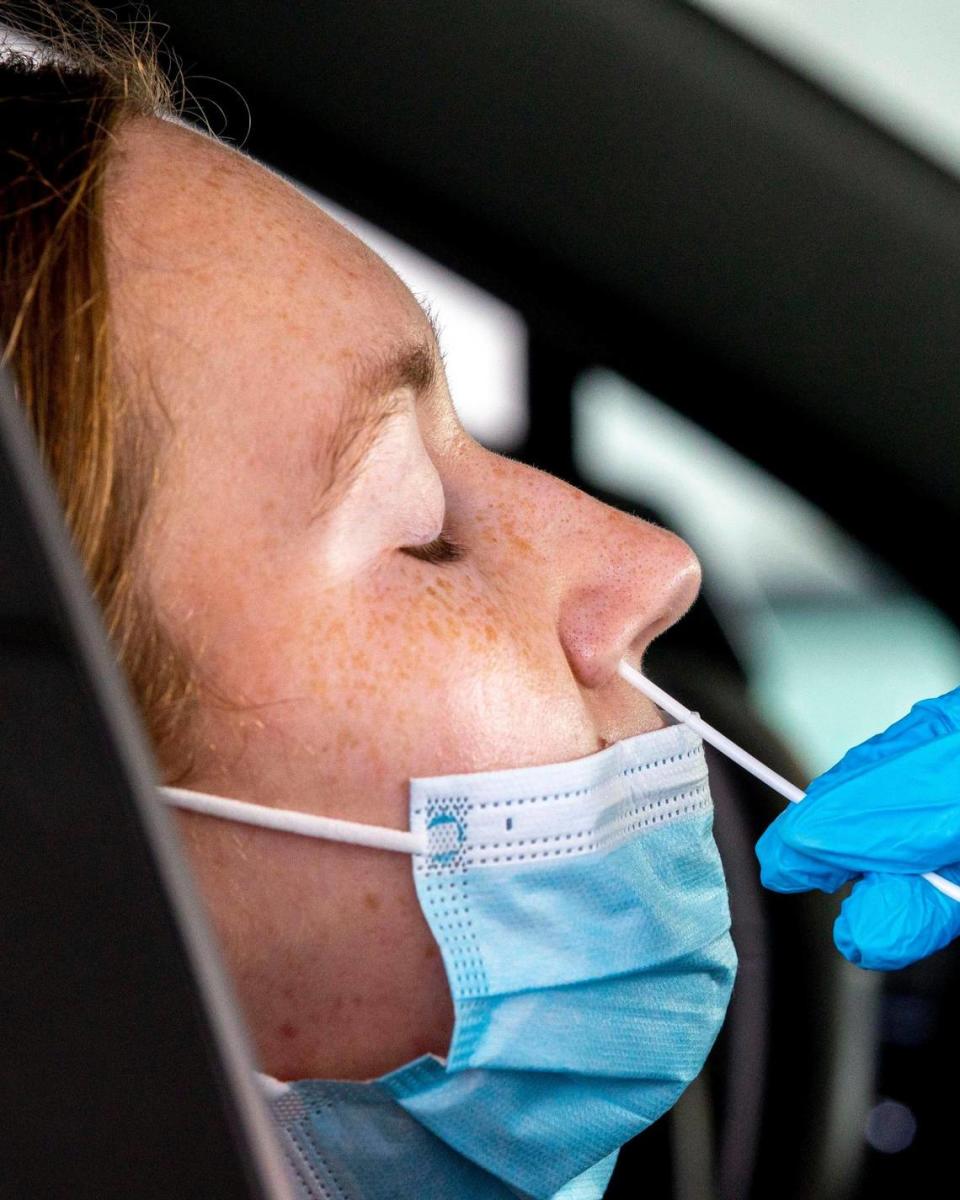 A car passenger sits in her vehicle as she allows a healthcare professional to swab her nose for a COVID-19 PCR Nasal Swab test at a Nomi Health testing center inside Tropical Park in Miami, Florida, on Tuesday, May 24, 2022.
