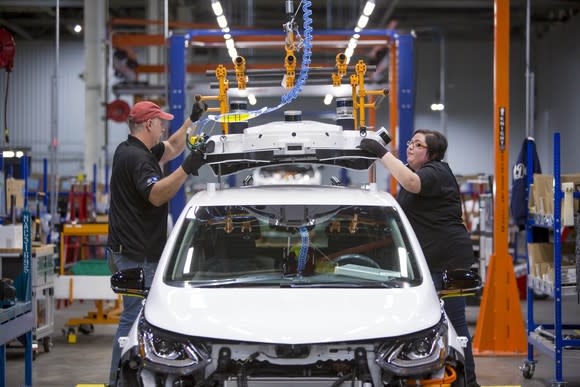 Workers at GM's Orion Assembly Plant in Orion Township, Michigan, are shown fitting a Chevrolet Bolt EV with a self-driving sensor array.