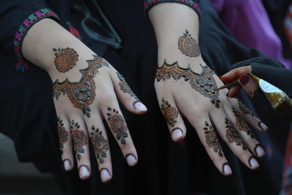 A beautician paints hands of customers with traditional henna in preparation for the upcoming Eid al-Fitr celebrations, in Karachi, Pakistan, Thursday, April 20, 2023. Eid al-Fitr marks the end of the Islamic holy month of Ramadan. (AP Photo/Fareed Khan)